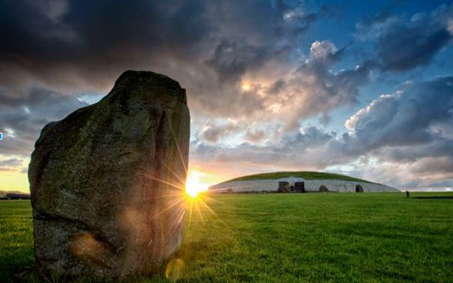 Summer Sun rising between a standing stone and Newgrange